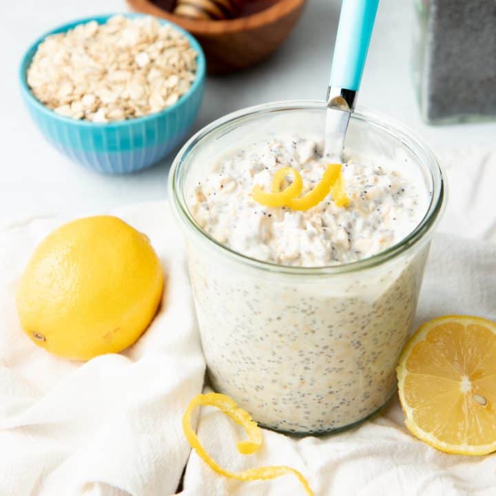 A jar is filled with lemon poppyseed overnight oats. It is topped with a twirl of lemon zest.