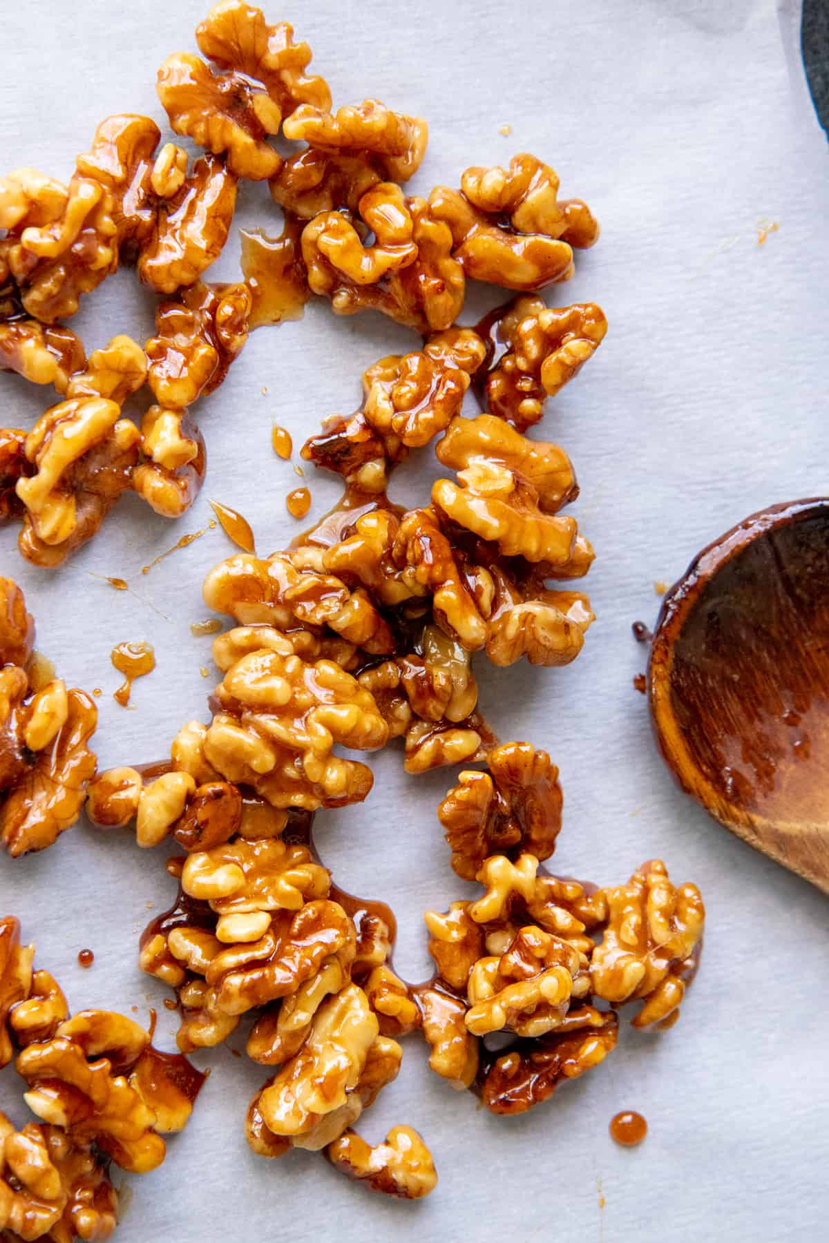 Maple candied walnuts are spread out on a piece of parchment paper.