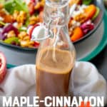 A bottle of maple vinaigrette sits in front of a bowl of salad. A text overlay reads "Maple-Cinnamon Vinaigrette."