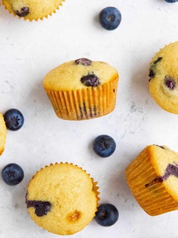 Mini muffins, some standing and some on their sides, on a counter with fresh berries around them.