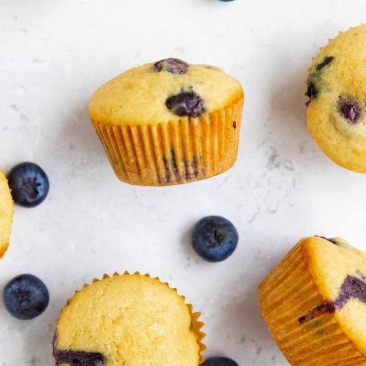 Mini muffins, some standing and some on their sides, on a counter with fresh berries around them.