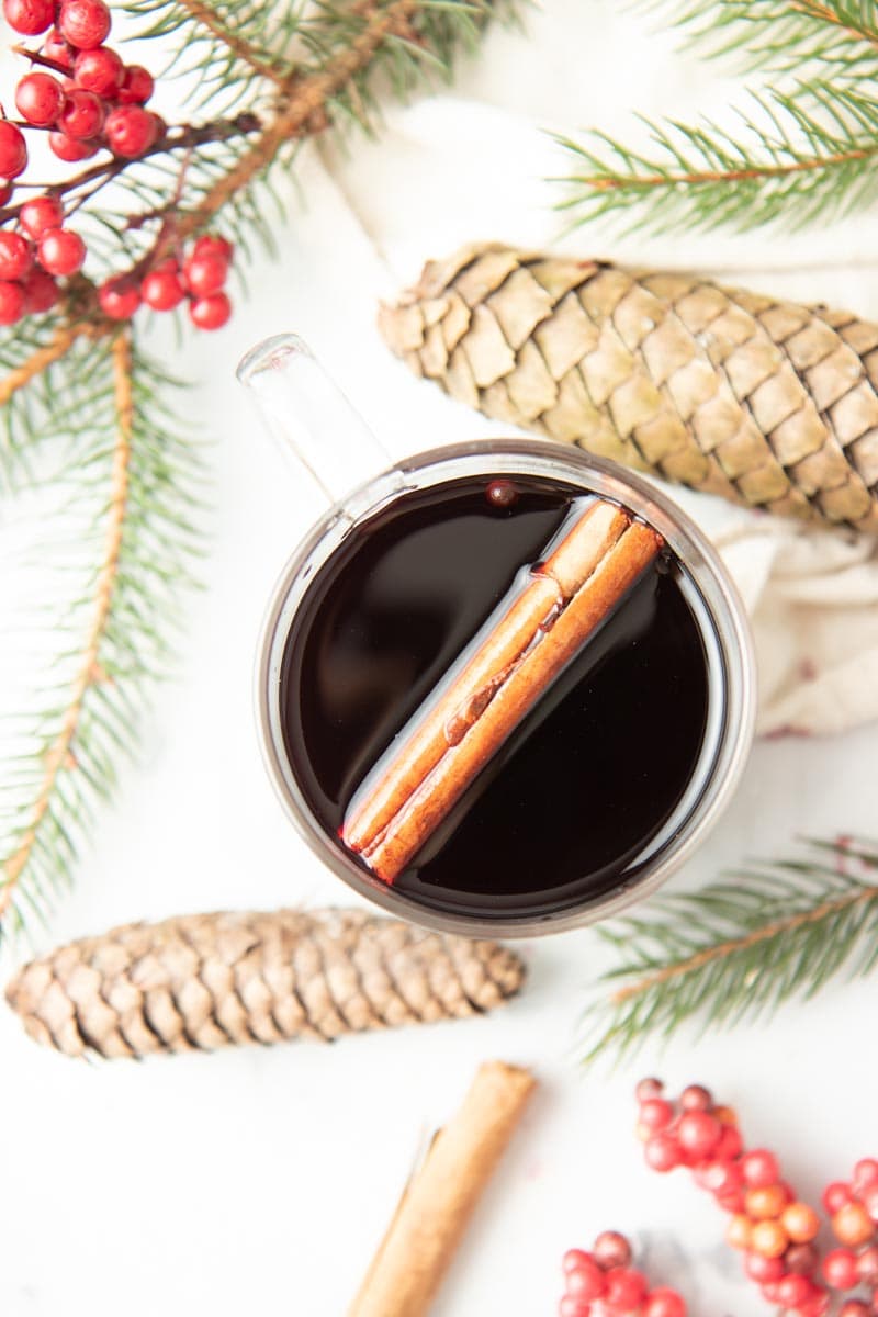 Overhead of a mug of wassail with a cinnamon stick floating on top.