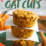 Three Pumpkin Spice Baked Oatmeal Cups stacked on a green plate, with pieces of parchment paper separating them. A text overlay reads "Baked Meal Prep Pumpkin Spice Oat Cups."