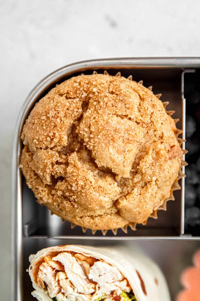 Overhead of a homemade muffin in one compartment of a bento-style lunchbox.