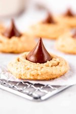 Close view of a peanut butter blossom cookie cooling on a rack.