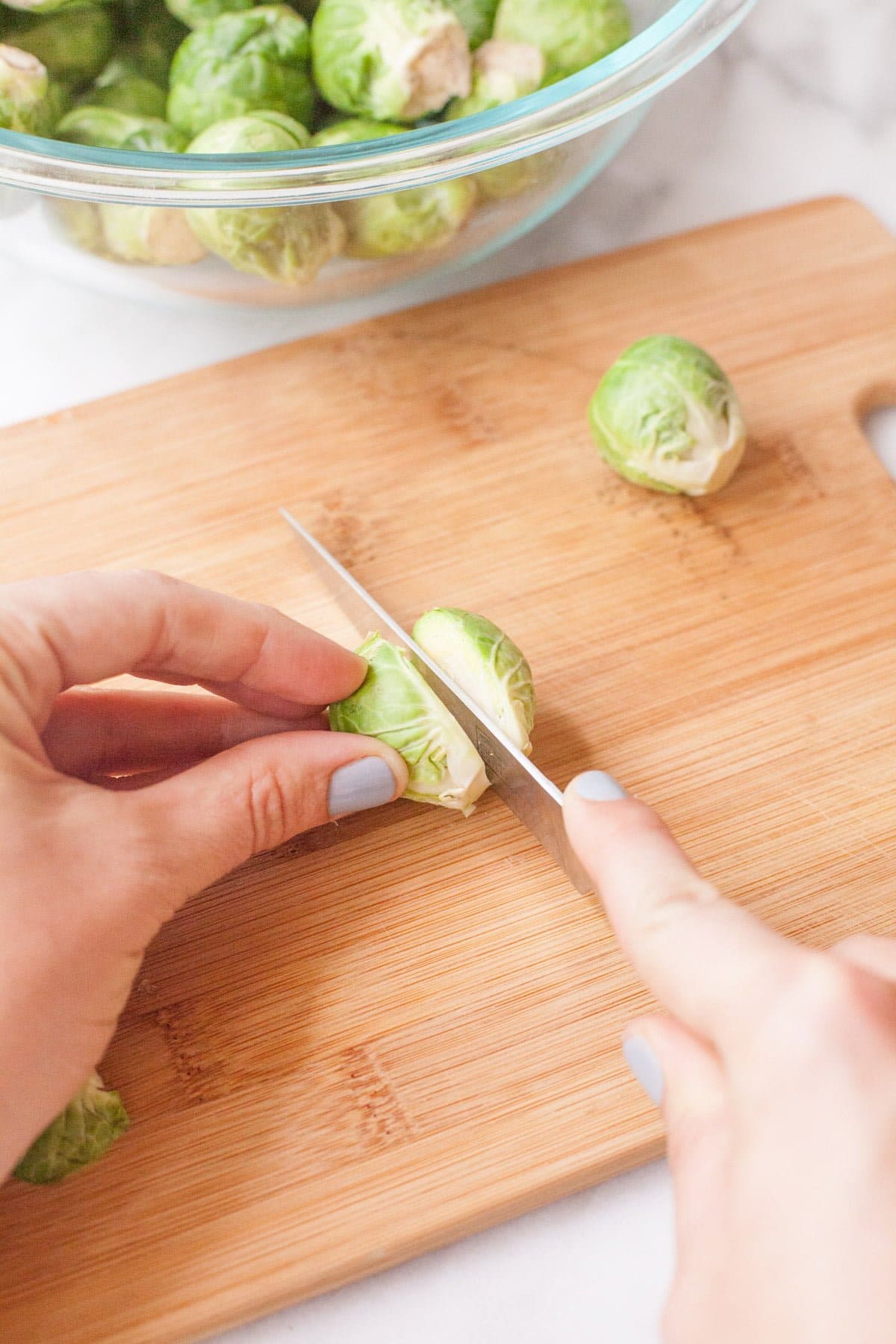 Hands cut a Brussel sprout in half