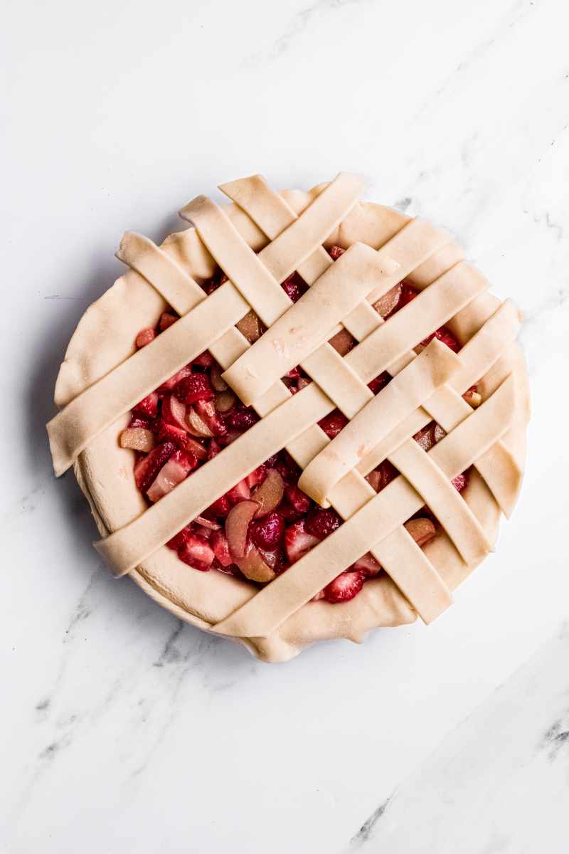 Strips of pie dough laid out and folded over to make a lattice weave over the filling mixture and bottom crust.