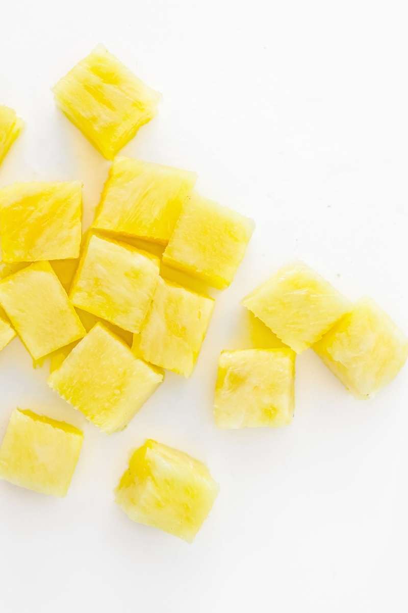 Top view of pineapple cubes in a pile on a white counter top.