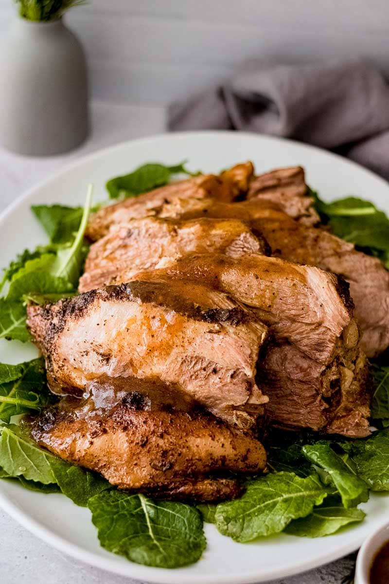 Close up of sliced and plated pork roast topped with gravy.