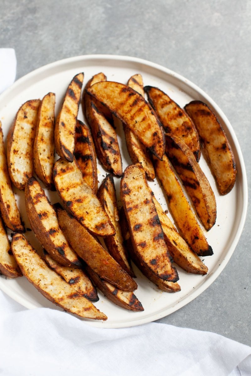 Side angle shot of Perfect Grilled Potato Wedges on a white plate