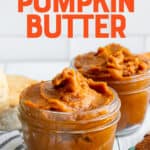 Two glass jars filled with Slow Cooker Pumpkin Butter, next to biscuits and a plate. A text overlay reads "Slow Cooker Pumpkin Butter."