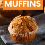 A pumpkin muffin in a paper liner with a bakery-style domed top rests on a kitchen linen. A text overlay reads, "Pumpkin Muffins."