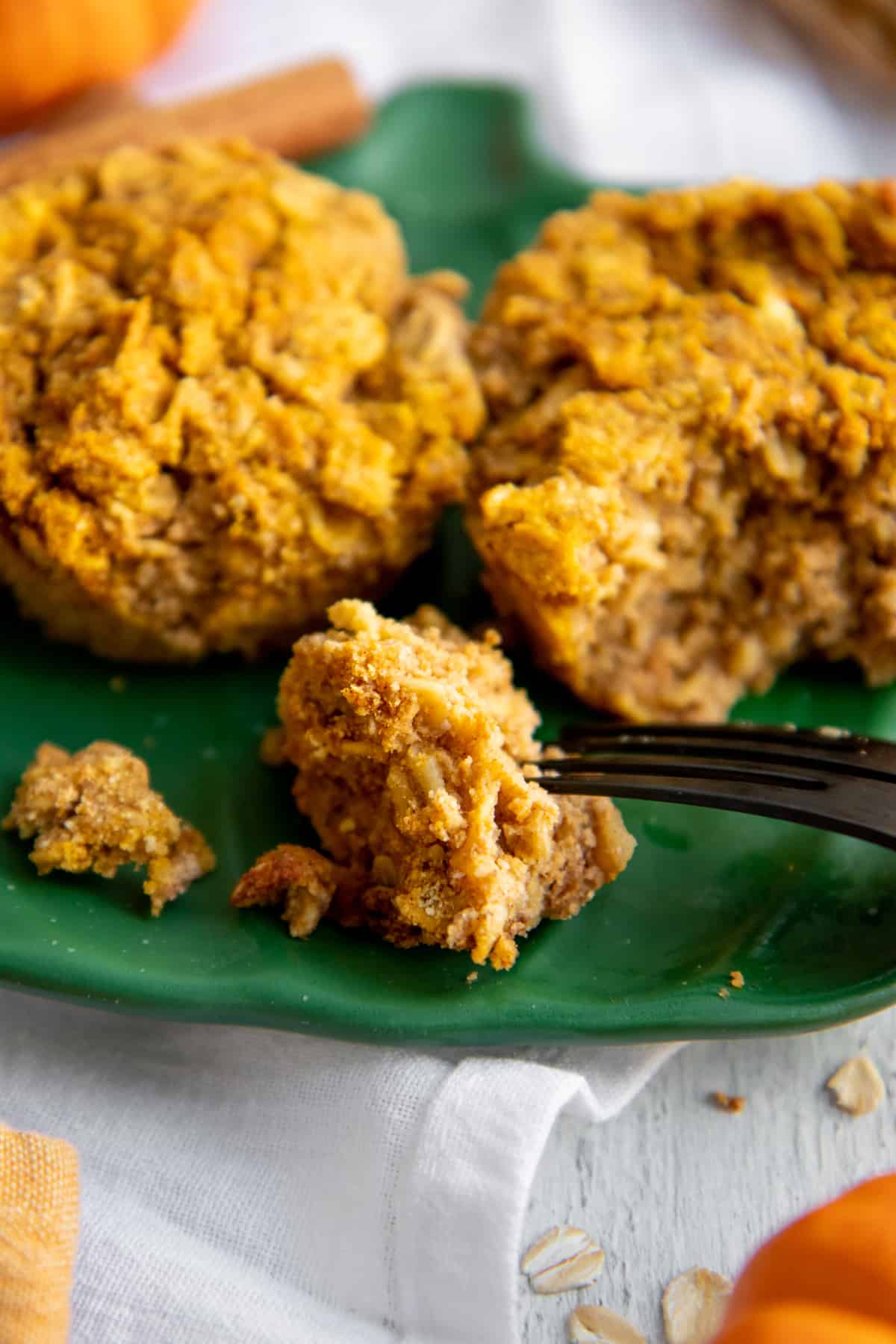 Fork cutting into a pumpkin oatmeal cup on a green plate.