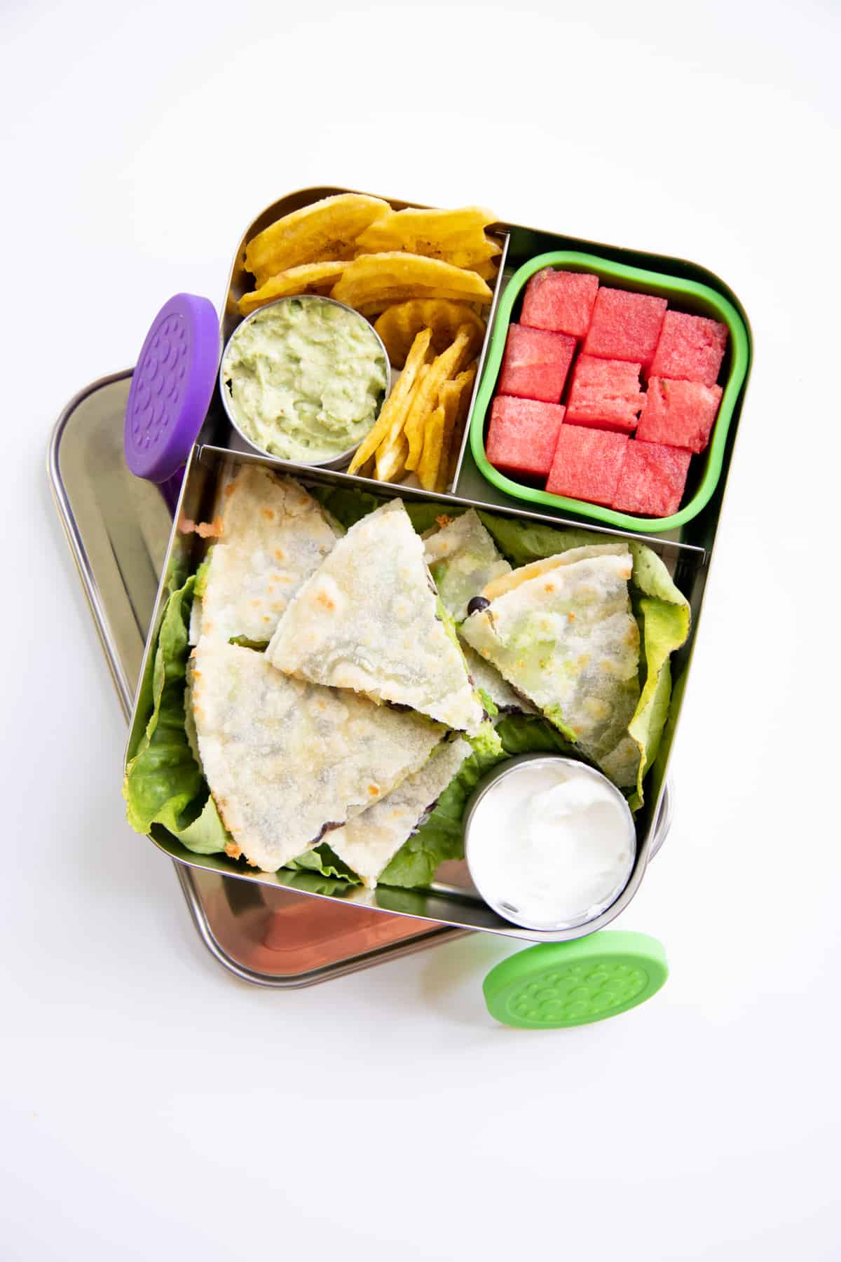 Stainless steel divided lunchbox with quesadilla, watermelon, plantain chips, and guacamole