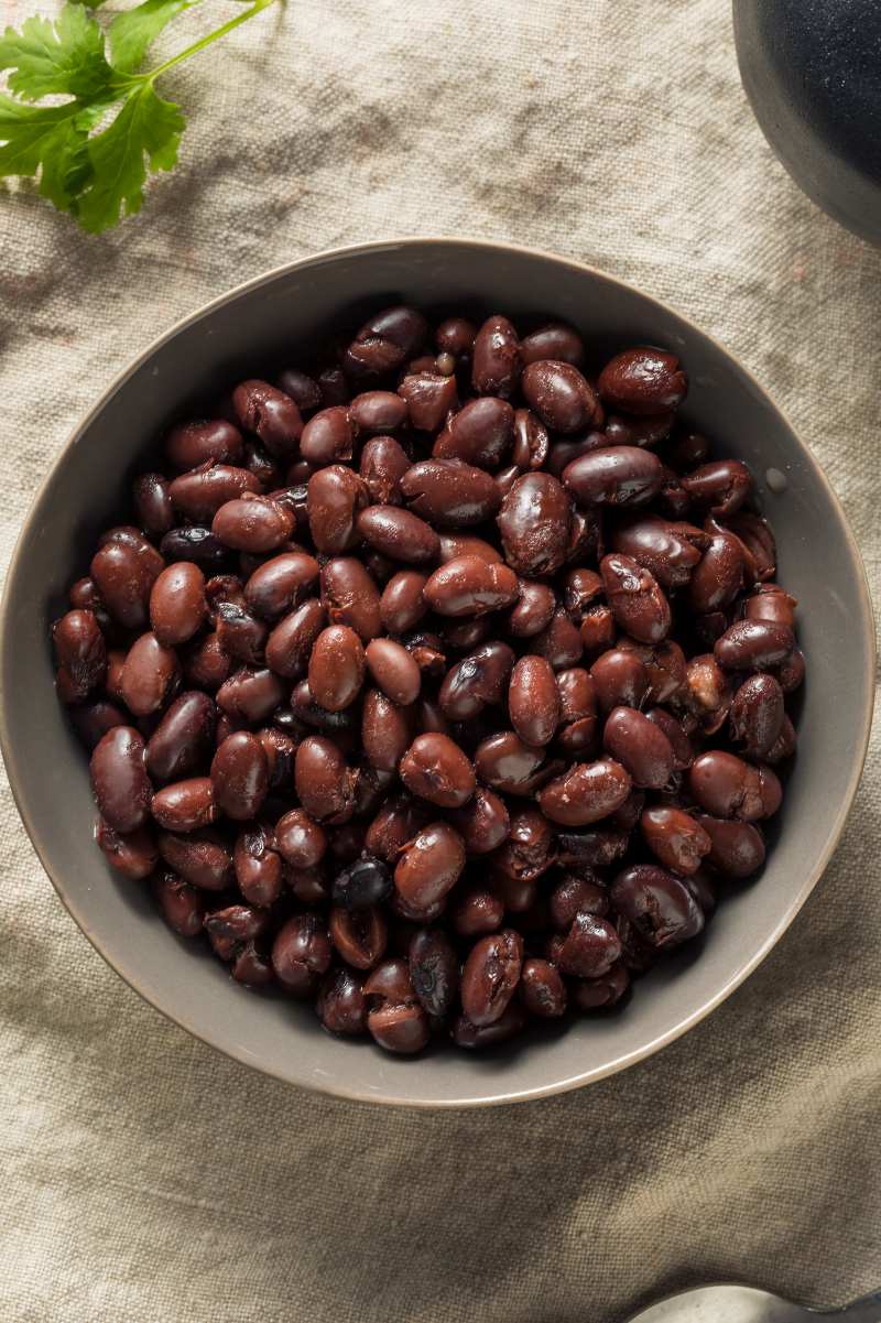 Overhead of a bowl of no soak black beans with fresh cilantro nearby.