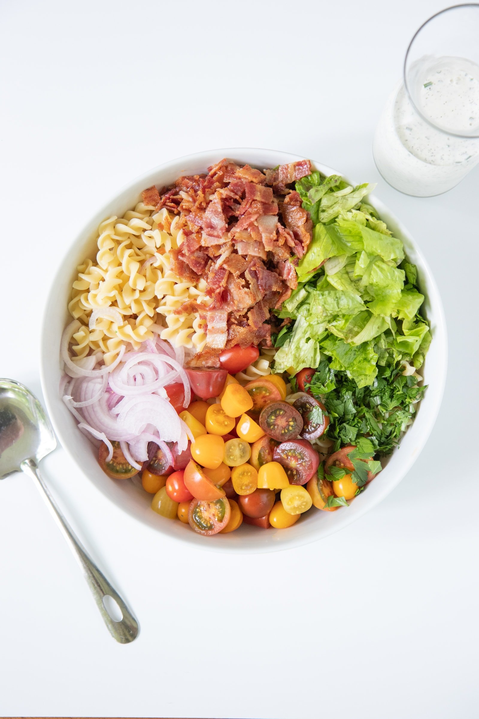 Ingredients for Ranch BLT Pasta Salad in a white bowl, before mixing