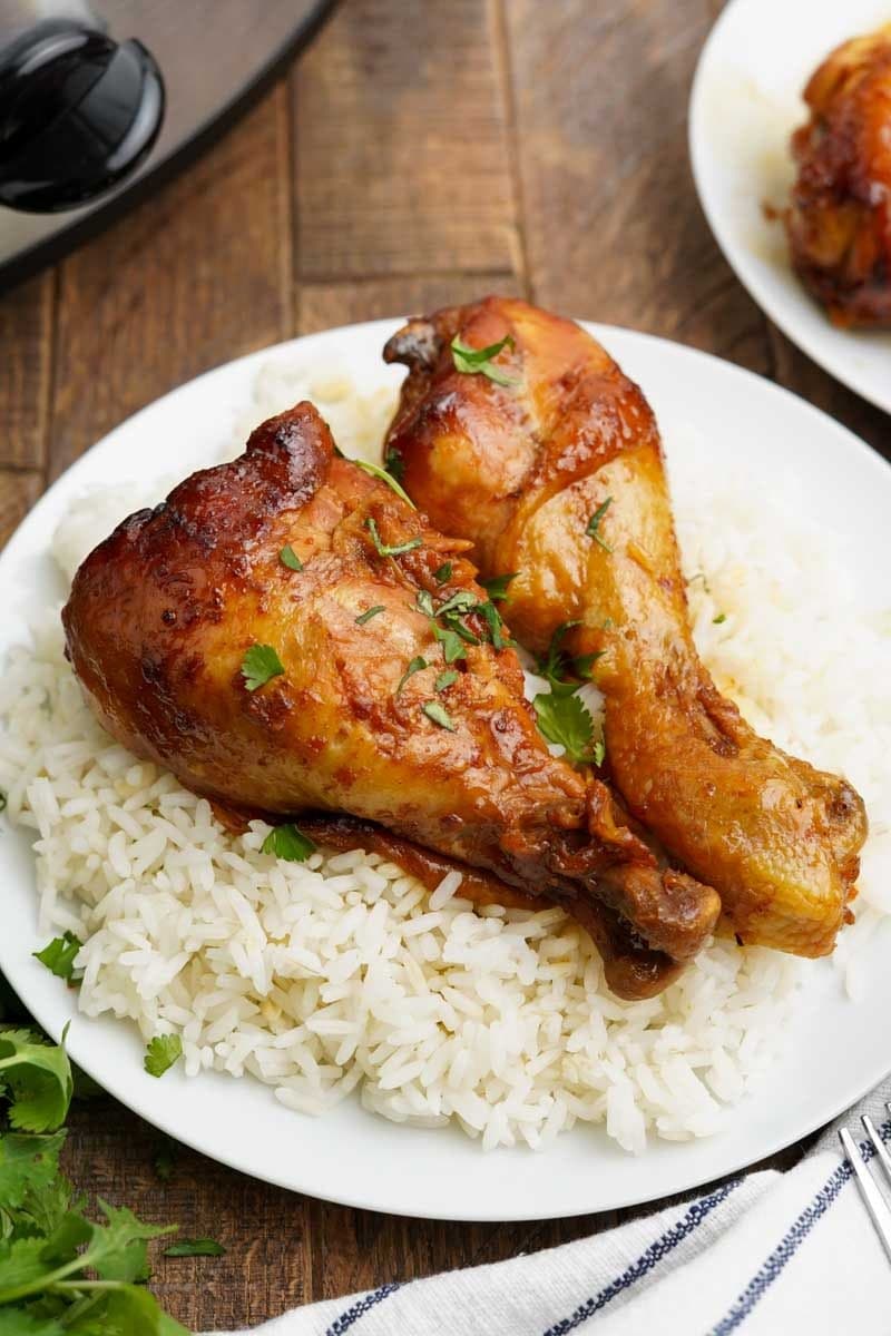 Slow cooker chicken served over rice on a white plate.