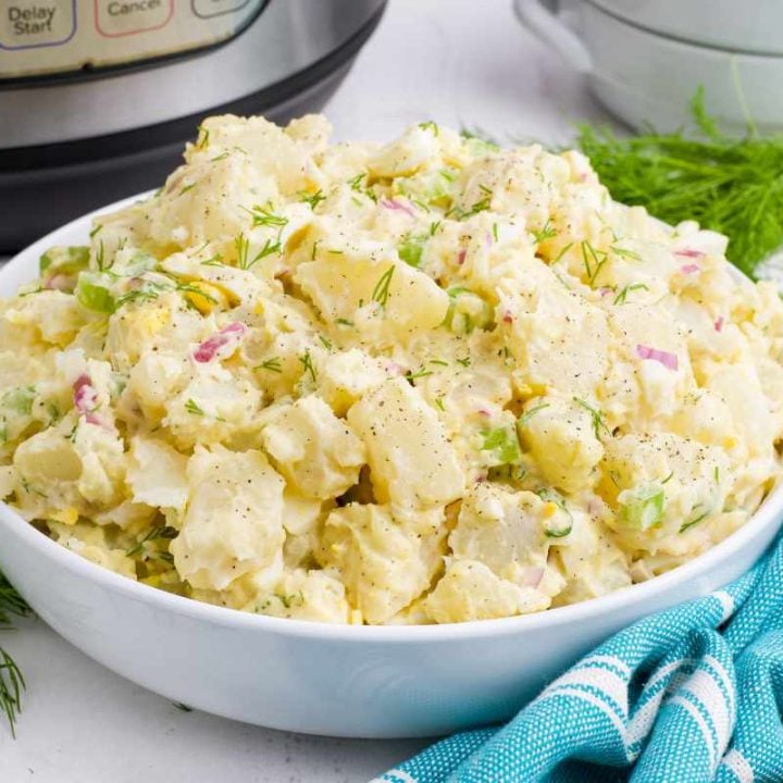 Close view of a white serving bowl piled high with creamy potato salad made in an instant pot.