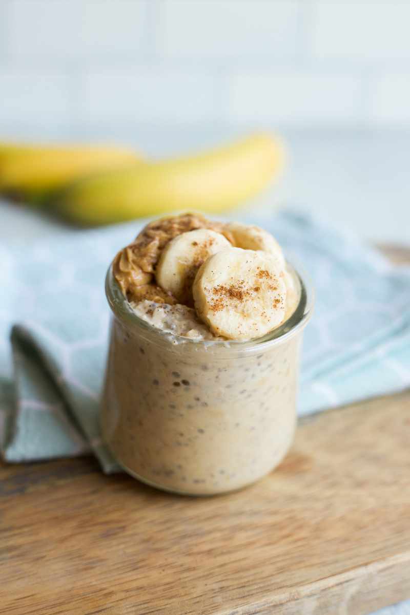 A single serving of oats topped with sliced fruit and cinnamon in a small glass jar.