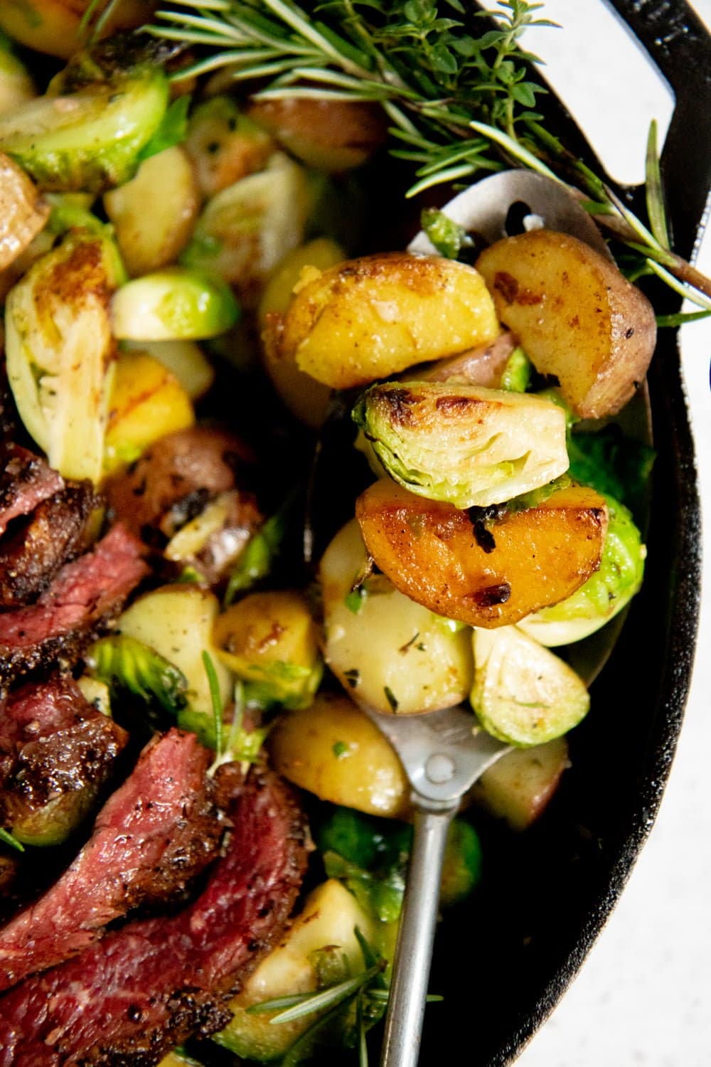 Close-up of cooked potatoes and Brussels sprouts in a cast iron skillet