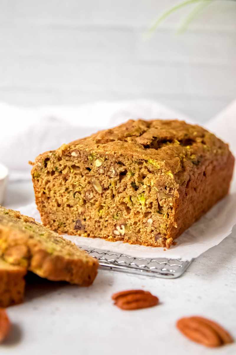 Sliced quick bread with courgette and pecans on a parchment lined metal cooling rack.