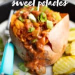 Sweet potato stuffed with Sloppy Joes filling on a plate, with a teal-handled fork and pickle slices next to the potato. A text overlay reads "Sloppy Joes Sweet Potatoes. Paleo & Whole30-Friendly."