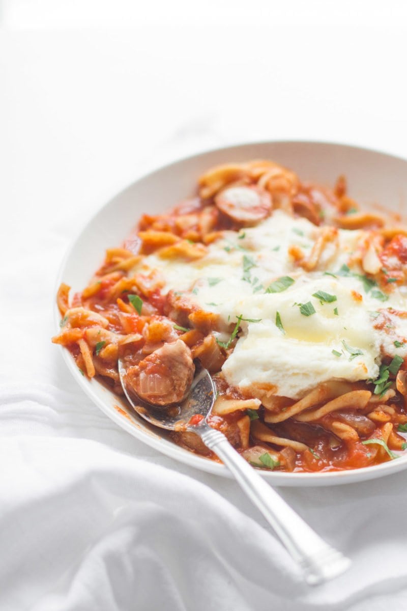 A spoon sits in a bowl of lasagna soup.