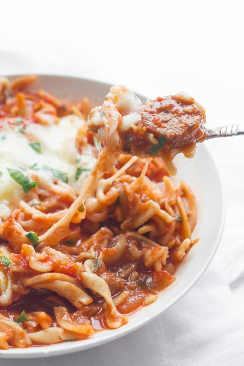 Slow Cooker Lasagna Soup sits in a bowl. A spoon takes out a bite.