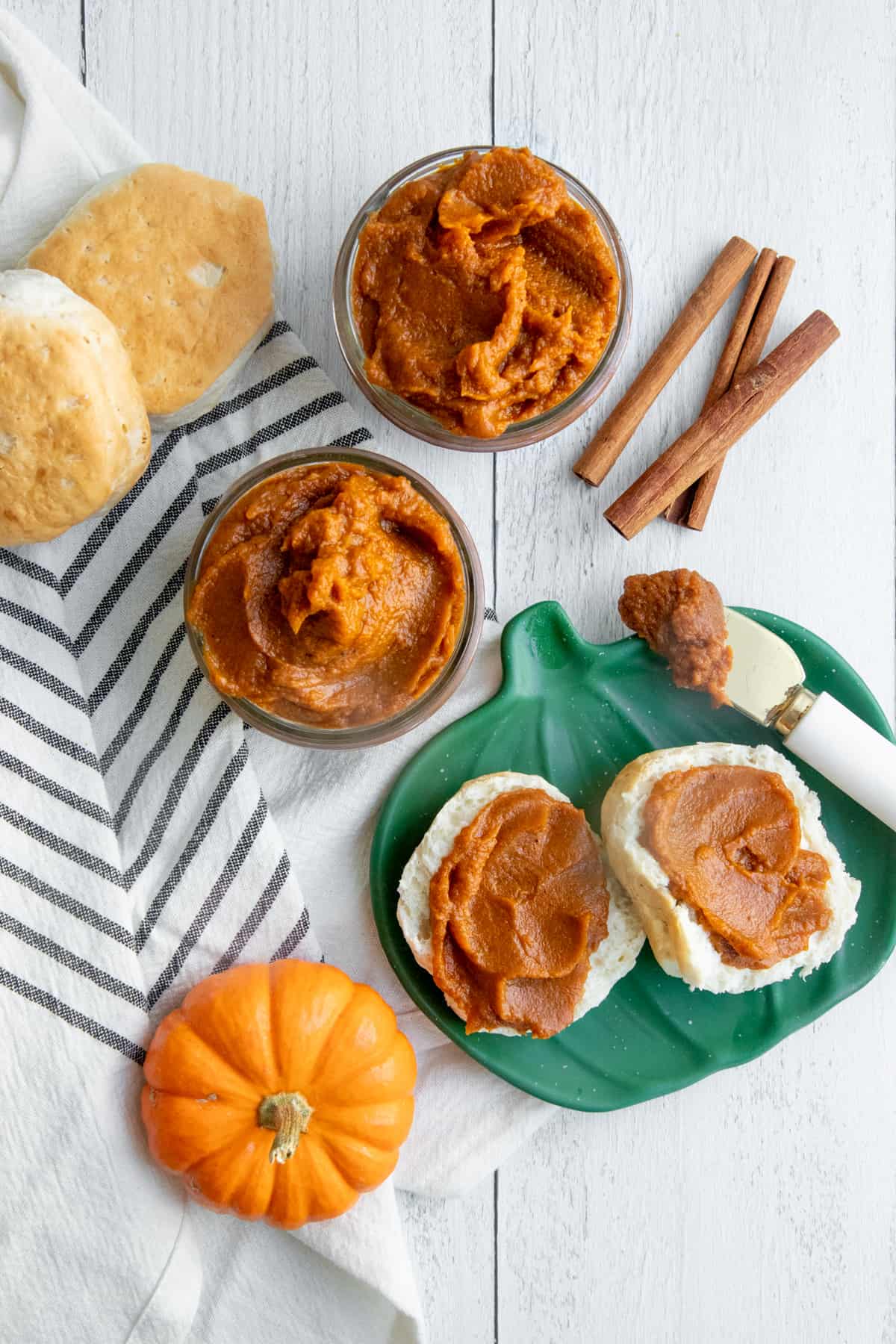 Pumpkin butter spread on a split biscuit, which is sitting on a pumpkin-shaped plate.