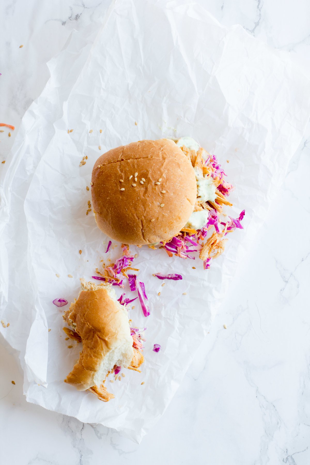 Overhead of two sliders on parchment paper, one of which is partially eaten.