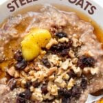 Slow cooker steel cut oats in a bowl drizzled with maple syrup and topped with chopped walnuts and dried fruit. A text overlay reads, "Slow Cooker Steel Cut Oats."