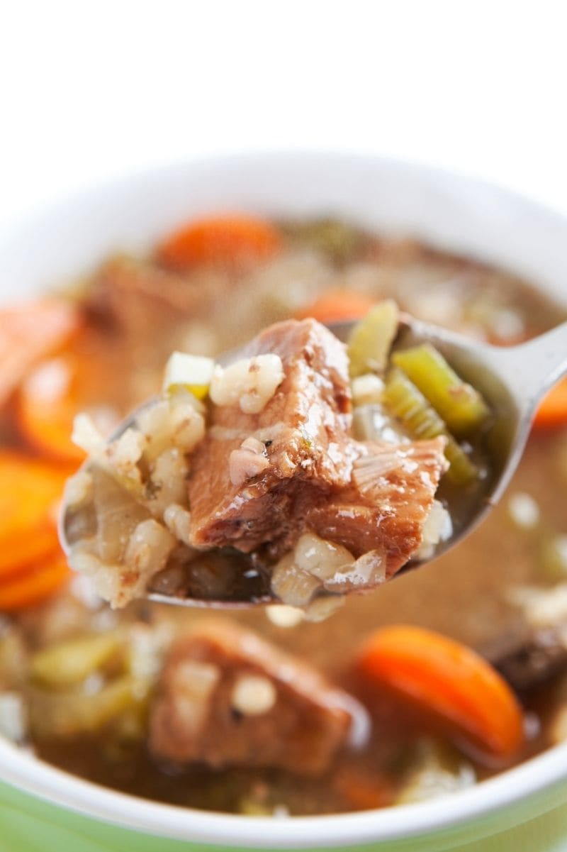 Tight view of spoonful of beef barley soup on a spoon.