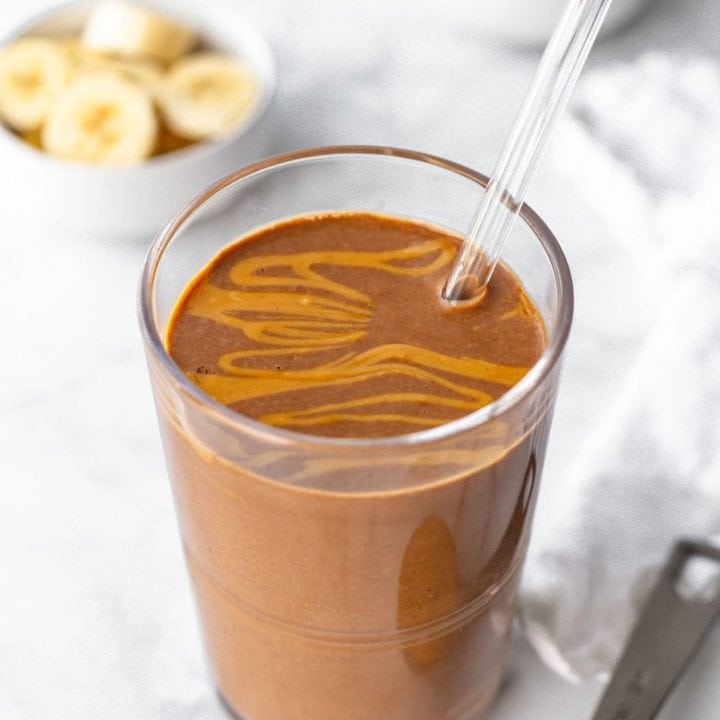 Close-up of finished smoothie in a glass with a reusable glass straw.