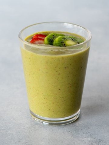 Top view of a strawberry kiwi smoothie in a glass topped with two thin slices of strawberry and kiwi.