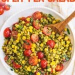 Overhead of serving bowl full of finished split pea salad with wooden serving spoon scooping up the first serving. A text overlay reads, "Summer Split Pea Salad."