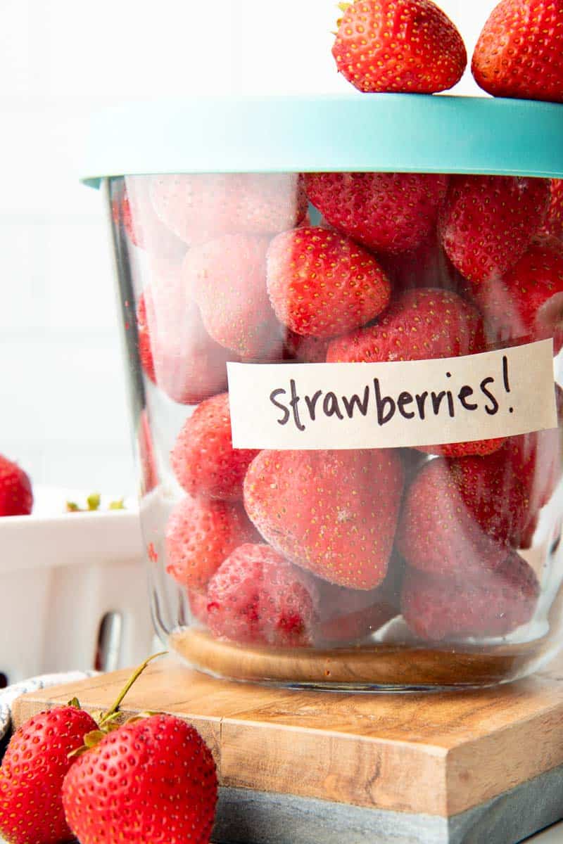 Close-up of glass container labeled strawberries filled with individually frozen whole strawberries.