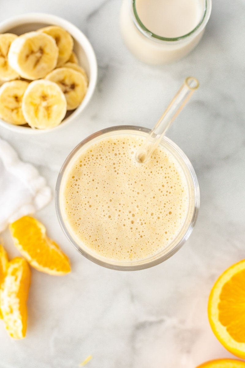 Top view of frothy smoothie with fresh ingredients around it.