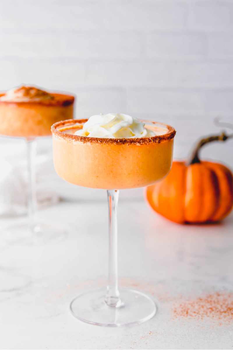 Two dessert cocktails garnished with whipped cream on a white counter.