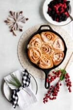 Overhead of a cast iron skillet filled with make-ahead vegan cinnamon rolls drizzled with icing.