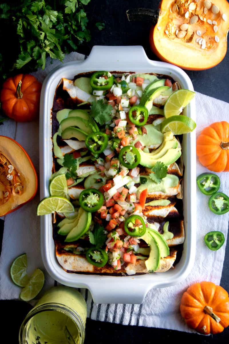 White casserole dish filled with Pumpkin and Black Bean Vegan Enchiladas