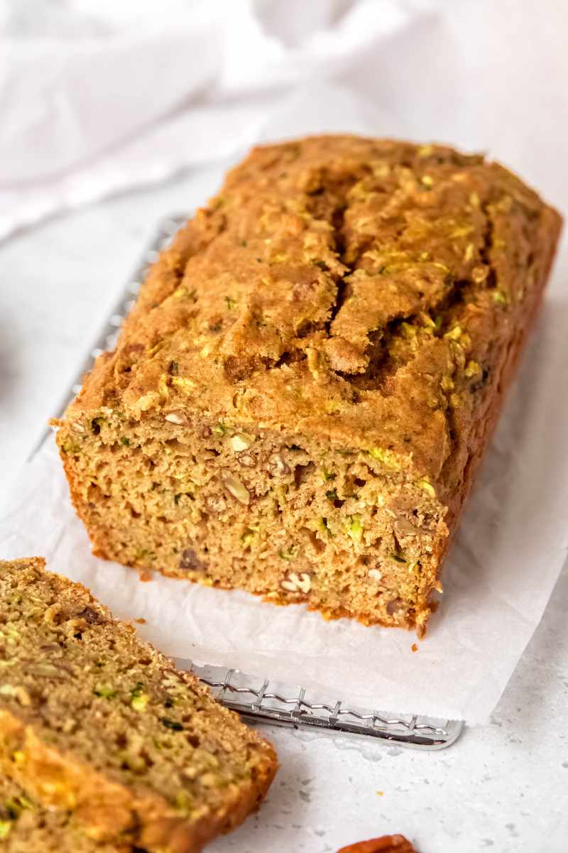 Close view of a loaf of whole wheat zucchini bread with slices cut for serving, showing the tender middle.